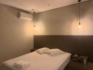 a bedroom with a white bed and two lights at Wish Suítes in Campinas
