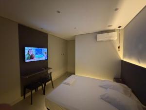 a bedroom with a bed and a tv on the wall at Wish Suítes in Campinas