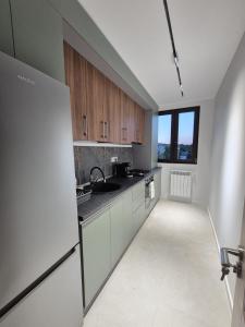 a kitchen with wooden cabinets and a white refrigerator at The Garden Apartment in Bîrlad