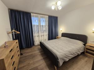 a bedroom with a bed and a dresser and curtains at The Garden Apartment in Bîrlad