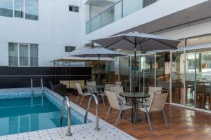 a pool with tables and chairs and umbrellas next to a pool at Hotel Libertad Pacasmayo in Pacasmayo