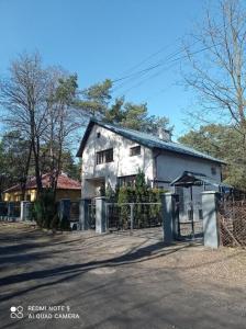 an old white house with a fence in front of it at TanieSpanie in Legionowo