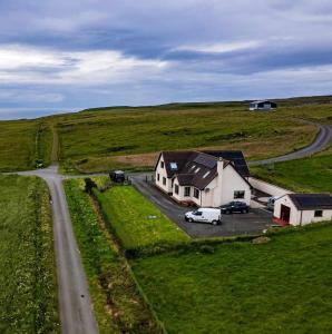 a house in a field with cars parked next to a road at Trumpan Cottage Bed & Breakfast in Trumpan