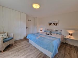 a bedroom with a bed with a blue blanket and a chair at Goting-Sonne in Borgsum