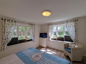 a bedroom with a bed and a tv and windows at Goting-Sonne in Borgsum