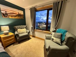 a living room with a couch and a chair and a window at Trumpan Cottage Bed & Breakfast in Trumpan