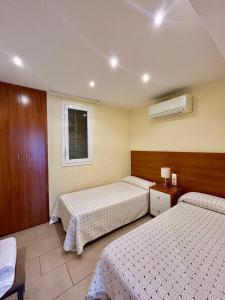 a hotel room with two beds and a window at Apartaments Tramuntana in Port de la Selva