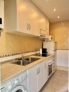 a kitchen with white cabinets and a sink at Apartaments Tramuntana in Port de la Selva +3 photos