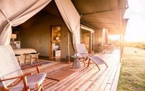 a tent with chairs and a bed on a wooden deck at Olopiro Stay in Maasai Mara National Reserve