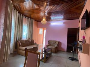 a living room with two chairs and a ceiling with wood at Résidence Le Refuge de Mbangue in Kofa