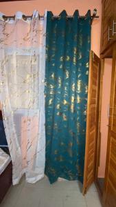 a bedroom with a blue curtain with fish on it at Résidence Le Refuge de Mbangue in Kofa