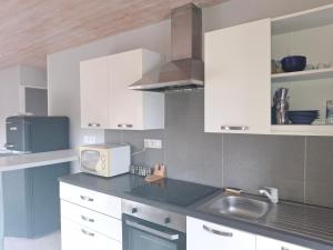 a kitchen with white cabinets and a sink and a microwave at Entre Terre et Mer in Malestroit