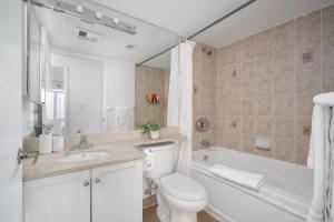 a bathroom with a toilet and a tub and a sink at Modern King Suite Steps to Eaton Centre in Toronto