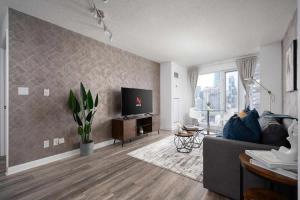 a living room with a couch and a flat screen tv at Modern King Suite Steps to Eaton Centre in Toronto
