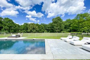 a swimming pool with lounge chairs and a fence at Whimsy Woods - 14 Acre Millbrook Estate with Pool in Millbrook