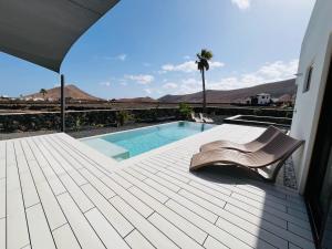 a deck with a chair and a swimming pool at Villa la Guancha in La Oliva