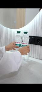a person holding two bottles of water on a counter at Small Cozy Spa Hotel in Aktobe