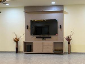 a flat screen tv on a wall with two vases at Desai Villa - Pawna Lake in Wadgaon