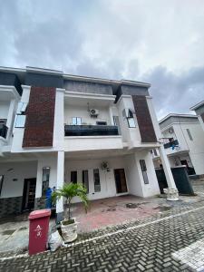 a white house with a palm tree in front of it at Emilomo Luxury Apartment in Idowu