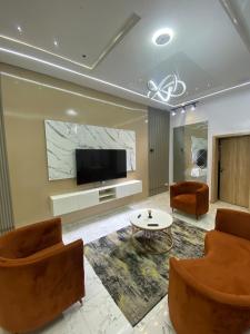 a living room with two chairs and a flat screen tv at Emilomo Luxury Apartment in Idowu