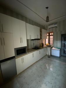 a kitchen with white cabinets and a tile floor at Emilomo Luxury Apartment in Idowu