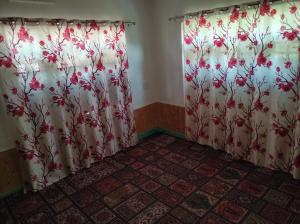 a room with two curtains with red flowers on them at Alpine Adventures Guest House Gurez in Gurais