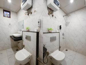a white bathroom with a toilet and a sink at Hotel The Caves Near IGI Airport Delhi in New Delhi +25 photos