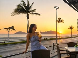 a woman sitting at a table with a drink at Olas Altas Inn Hotel & Spa in Mazatlán