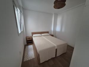 a white bedroom with a bed and a window at Playa Los Náufragos Torrevieja in Torrevieja