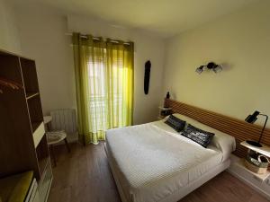 a bedroom with a bed with white sheets and a window at Céret hyper centre - Cozy T2 in Céret