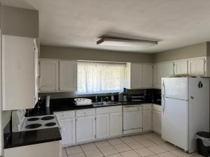a kitchen with white cabinets and a white refrigerator at Cozy nest in Coquitlam
