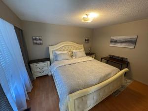 a bedroom with a bed and two tables and a window at Cozy nest in Coquitlam