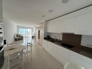 a kitchen with white cabinets and a table and chairs at AwayDays - 72 - Ocean View Studio in Empuriabrava