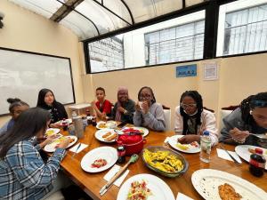 a group of people sitting around a table eating food at Casa Colon Quito Bed & Breakfast Hostel in Quito