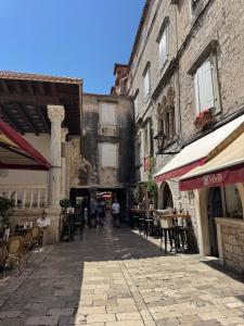 an empty street with tables and chairs and buildings at Boutique Central Square Hostel in Trogir