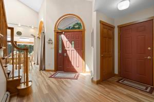 a hallway with two wooden doors and a staircase at Serene waterfront home w/ a dock, large deck & amazing views! in Dyer Cove