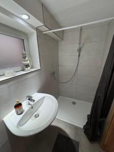a bathroom with a white sink and a shower at Toms FeWo in Losheim