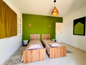 two beds in a room with a green wall at Wostel Djerba Downtown in Houmt Souk