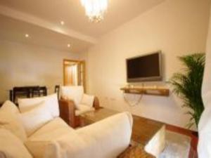 a living room with white furniture and a flat screen tv at Livingtarifa Apartamento El Nido in Facinas