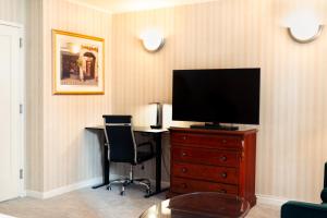 a room with a television on a dresser with a desk at Hotel Stanford in New York