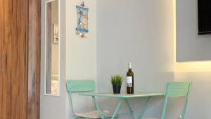 a table with a bottle of wine and two chairs at Magdalena Elegant Studios in Neoi Epivates