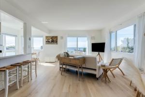 a living room with a desk and chairs and windows at Bella Surf in Avila Beach