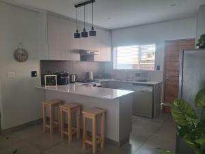 a kitchen with a counter and some stools in it at SafeHaven 45 in George