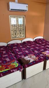 two beds in a room with a window at Parshotam Home Stay in Dwarka