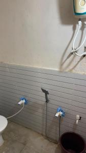 a bathroom with a toilet and a hose on the wall at Parshotam Home Stay in Dwarka