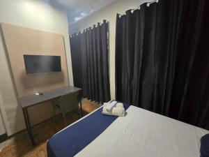 ein Schlafzimmer mit Bett, Schreibtisch und Fernseher in der Unterkunft Hotel Divinopolis Center - Alguel de Temporada in Divinópolis