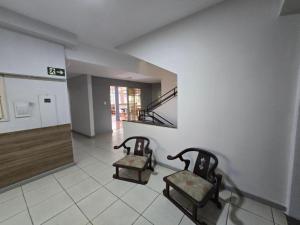 Zwei Stühle stehen in einem Raum mit einer Treppe in der Unterkunft Hotel Divinopolis Center - Alguel de Temporada in Divinópolis