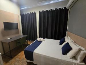 ein Schlafzimmer mit Bett, Schreibtisch und Fernseher in der Unterkunft Hotel Divinopolis Center - Alguel de Temporada in Divinópolis