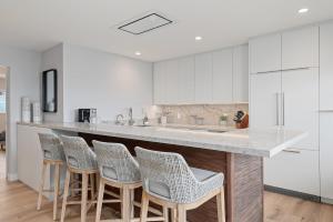 a kitchen with white cabinets and bar stools at Carpinteria Shores CS 107 in Carpinteria
