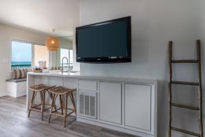 a kitchen with a bar with stools and a tv on the wall at Carpinteria Shores CS 312 in Carpinteria